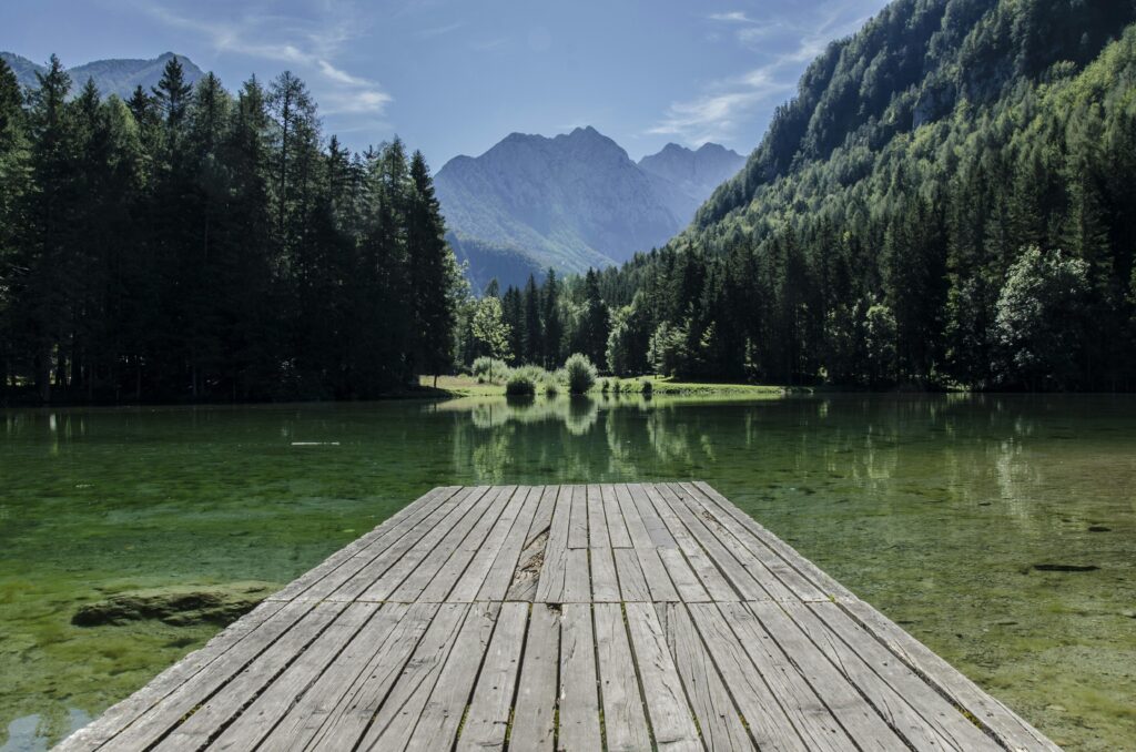 Tranquil lake scene with mountains and dock in Kranj, Slovenia.